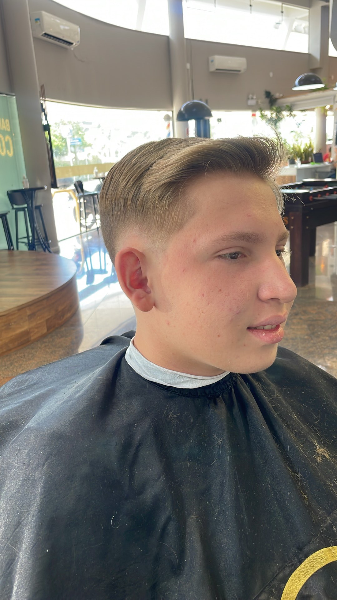 Corte com degradê baixo e topo penteado, visto de perfil